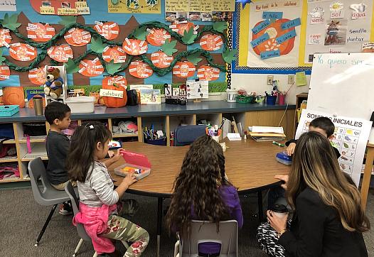 Kindergarteners sit around school table.