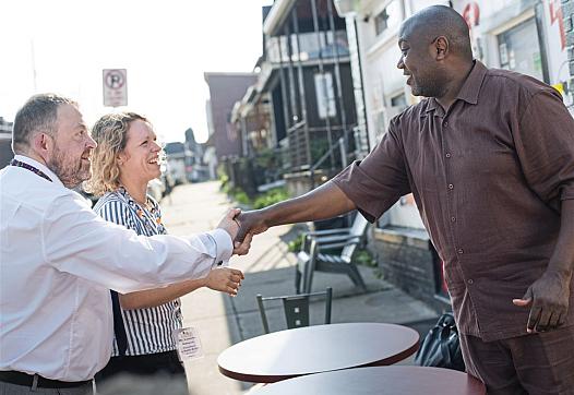 John O'Dowd, left, and Catriona Milosevic, of the UK's National Health Service, meet grocer Carl Lewis.