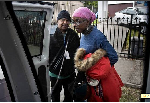 Driver Calvin Woodard opens his van door for Carmel Neal.