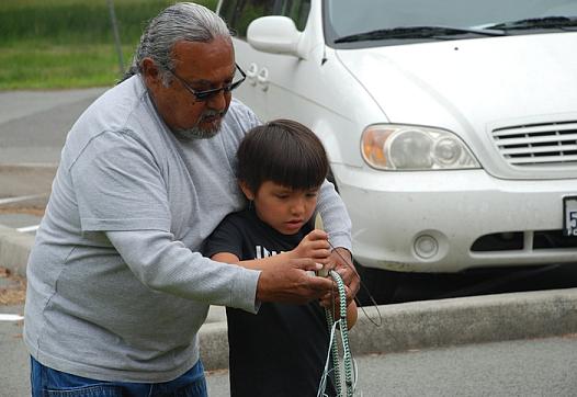 David Gensaw Sr. shows Dean McCovey how to repair a gill net at Margaret Keating Elementary School's Au Minot Day celebration.