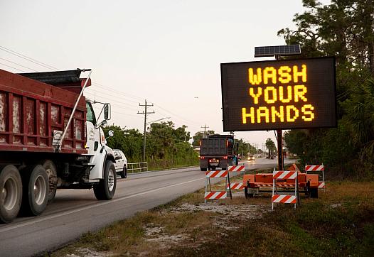 A sign along Immokalee Road encourages people to wash their hands and stay six feet apart to limit the spread of coronavirus in 