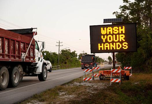 A sign along Immokalee Road encourages people to wash their hands and stay six feet apart to limit the spread of coronavirus in