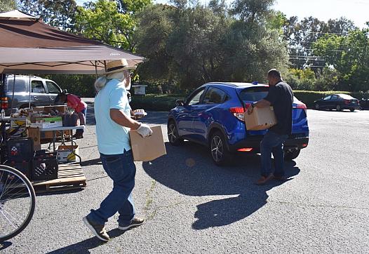 Volunteers help load boxes of food into vehicles after asking drivers how many boxes of food they want on June 4, 2021.