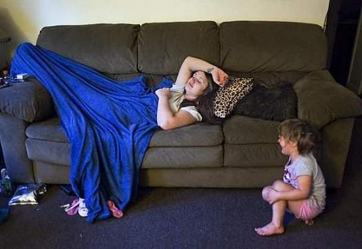 Brittany Crouch suffers through withdrawal symptoms, the day before leaving for treatment in Lexington, as her youngest daughter Kaylee Adams, 3, cries at the foot of the couch inside Crouch's brother's apartment living room in Frenchburg, Ky.