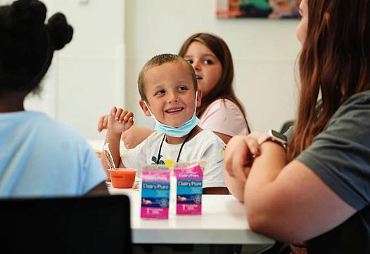 Timmy Schoolcraft, 6, smiles at library volunteer Reta Borton, 15, during the free summer lunch and snack program at the South H