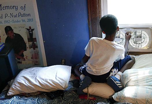 Jayden Lawson, now 9, lost his father to violence in 2013. At Jayden’s left is a poster from his father’s memorial service.