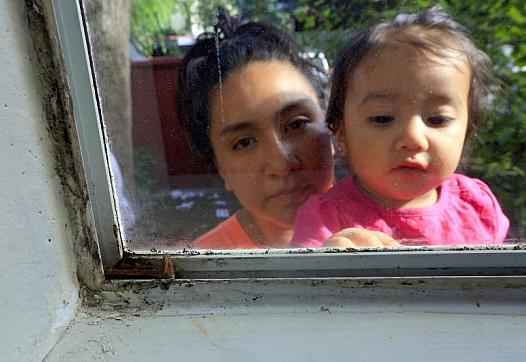 Guadalupe Vargas with her daughter Jaylani, 1, outside their mold covered bedroom window at the Walnut Creek Apartments.