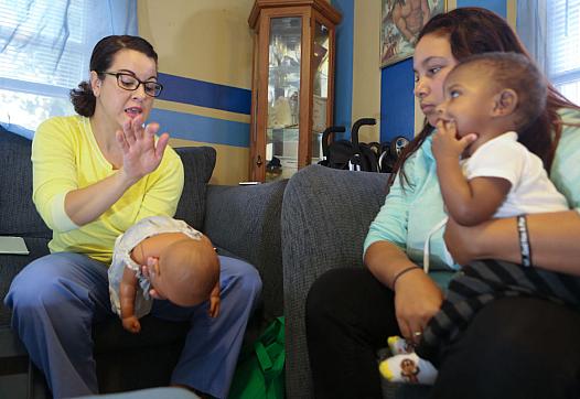 Nurse-Family Partnership nurse Amber Burleson shows D'Ondra Gomes, holding her 6-month-old son, Kai'Dian.