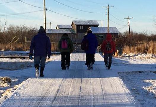 The Calricaraq team walks across the village's wooden sidewalks. 