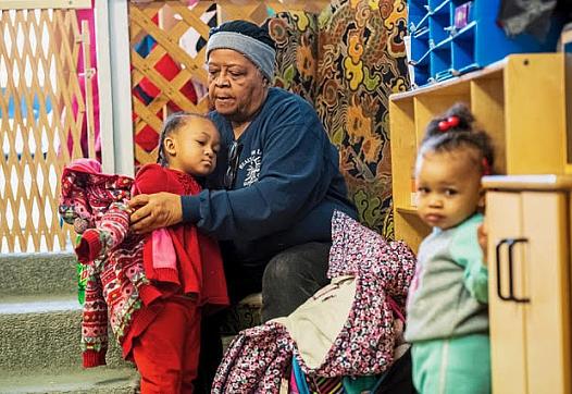 Evelyn West, great grandmother of Kee'Mayah West, 2nd grader, of North Braddock, Pa., dresses children at Great Start Day Care i