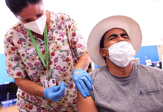 Registered nurse Sue Dillon administers a dose of the Pfizer COVID-19 vaccine to a person at a clinic in Wilmington, California.