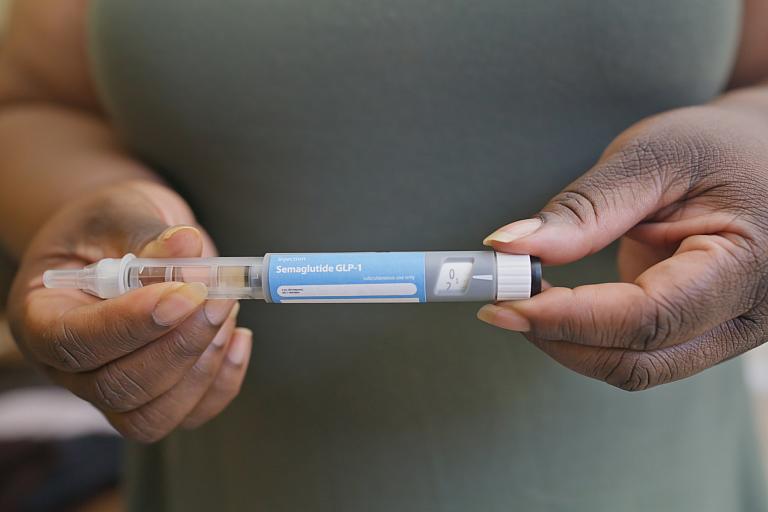 Photo of a Black woman holding GLP-1 medication.