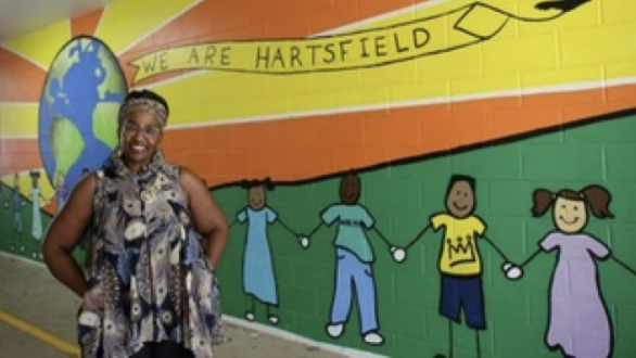 Dr. Rhonda Flanagan-Blackwell standing near a bright, rainbow mural painted on the halls of her school