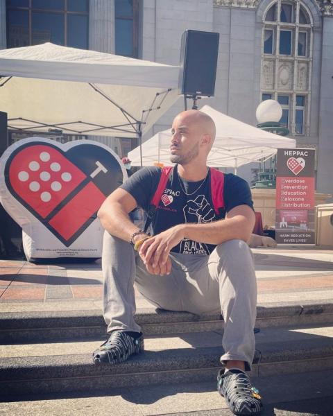 Braunz E. Courtney sits on the steps of Oakland’s Oscar Grant Plaza on August 31—HEPPAC set up a booth to commemorate International Overdose Awareness Day, giving out free food and hosting Narcan trainings. (Courtesy of HEPPAC)