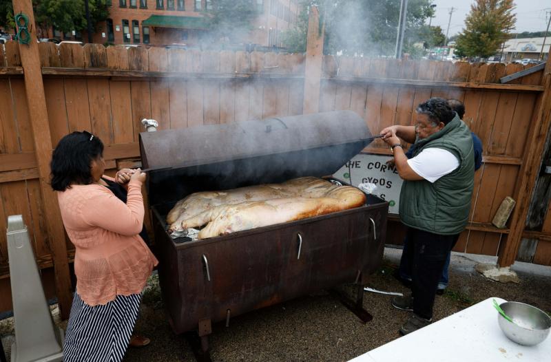 Before coronavirus arrived, Irene Maun Sigrah, a health worker focused on the care of Pacific Islanders living in America, left, assists Maitha Jolet during an annual community hog roast October 5, 2019 in Dubuque, Iowa. | M. Scott Mahaskey / POLITICO