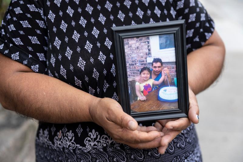 Candelaria Lucero holds an old photo of her husband Margarito and daughter Isamari. Margarito died of COVID-19 in May. Manuel Martinez / WBEZ