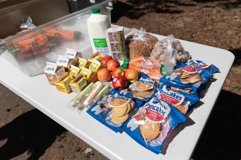An assortment of food, including milk, pancakes, apples, carrots, pasta, raisins and cheese are ready for distribution at Los Robles Ronald McNair Academy in East Palo Alto on April 28. Photo by Magali Gauthier.