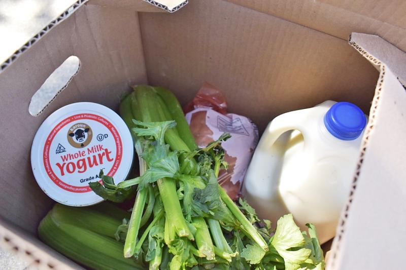 The contents of a recent Farmers to Families food box included milk, yogurt, celery, potatoes and frozen meat, all packed together and left on the street without refrigeration for anyone to pick up. Photo by Kate Bradshaw.