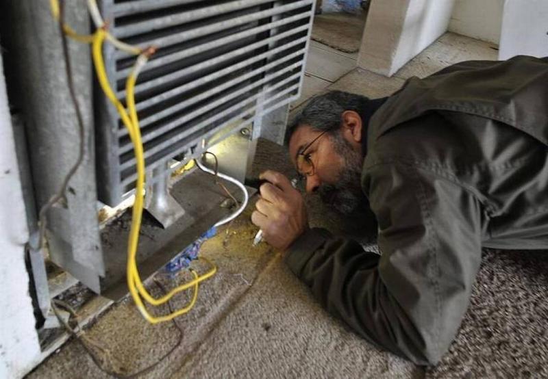 In 2016, city code enforcement inspector John Tanksley examines a broken heater — improperly hooked up and with bare wires exposed — at a Fresno apartment complex. The Fresno City Council approved a rental housing inspection program in 2017. JOHN WALKER JWALKER@FRESNOBEE.COM