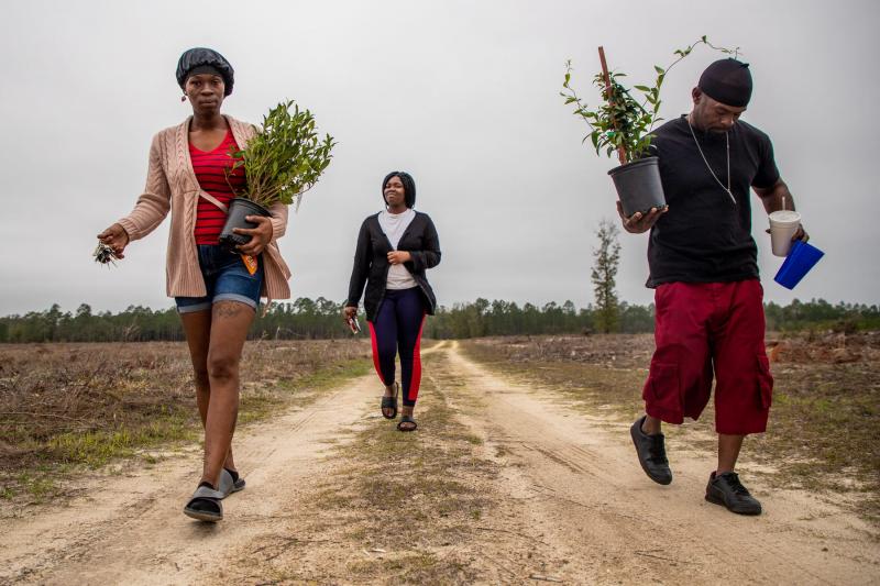 Koquisha Cook, 35, left, and her boyfriend Kevin Moore carry plants as they walk to Noonie's gravesite. Jamirica "Noonie" Cook, 15, was shot and killed last year in her home at Springfield Apartments. Noonie's sister Sharail “Sugar” Sampson, 14, carries a heart-shaped box of chocolates to leave on her sister's grave. ALICIA DEVINE/TALLAHASSEE DEMOCRAT