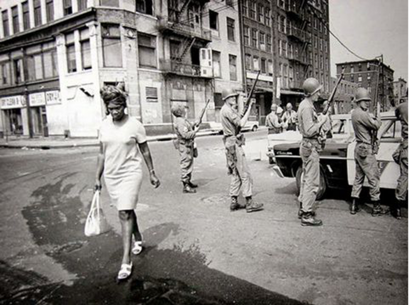 A woman walks past National Guard troops and State Police officers during the riots in Newark that took place from July 12-17, 1967. Star-Ledger archives