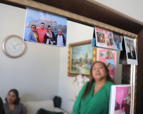 Ivonne Estela Ramos, originally from El Salvador, stares at photos of her family from her humble studio in San Francisco's Bayview neighborhood. Like many Latino immigrants during the pandemic, Ramos depleted her savings and risked her life finding work to pay the rent. Photo: Alexis Terrazas