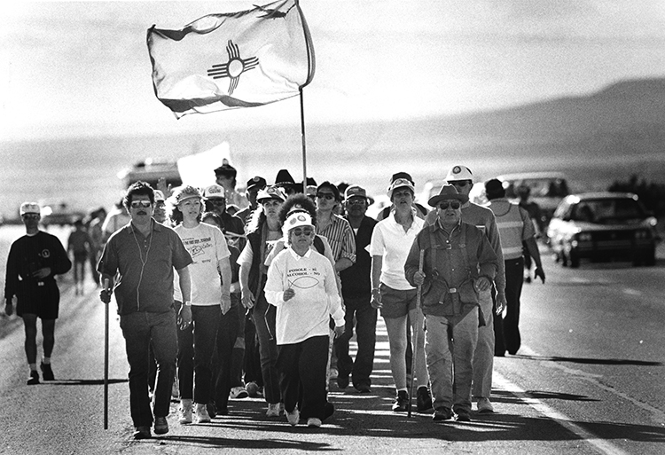 People walk on Interstate 25 from Gallup to Santa Fe during “Journey for JoVita,” a protest against drunk driving in 1989. CREDIT: Larry Beckner, courtesy of the Palace of the Governors Photo Archives, (NMHM/DCA), HP.2014.14.744