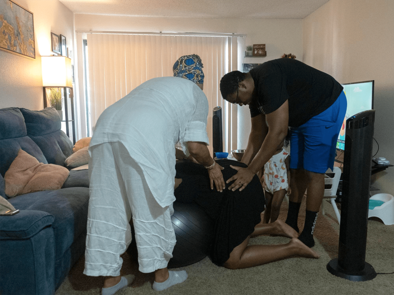 Doula, Karen Sykes guides David Morrow through an exercise that will support his wife’s labor experience and help her with pain during a home visit in Chino, CA. (Aryana Noroozi for Black Voice News/CatchLight Local). June 26, 2022.