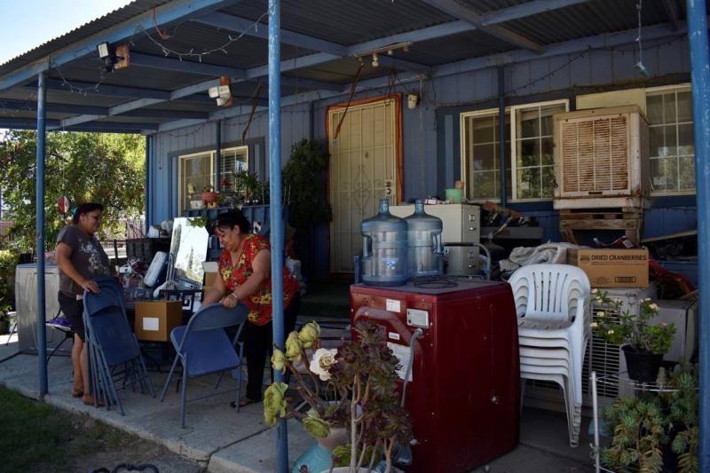 Julia Mendoza, left, and Blanca Gomez, right, wipe the dust off folding chairs at Gomez’s home on Aug. 19, 2022. When they can’t find relief from the heat inside Gomez’s home or on her front porch, the two friends sit under a tree in an abandoned parking lot. ldiaz@fresnobee.com LAURA S. DIAZ