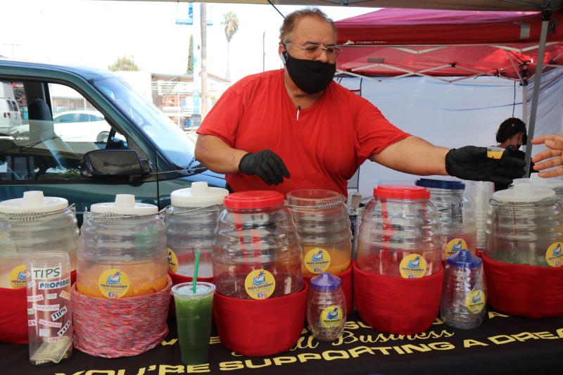 Cesar Benitez offers samples to those passing by, free shots of cucumber, melon and watermelon-flavored aguas.