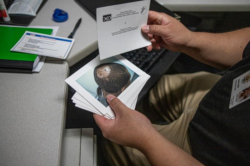 Hou Vang shows the postcards he carries to show people what syphilis symptoms can look like on June 9, 2022. Photos by Larry Valenzuela, CalMatters/CatchLight Local