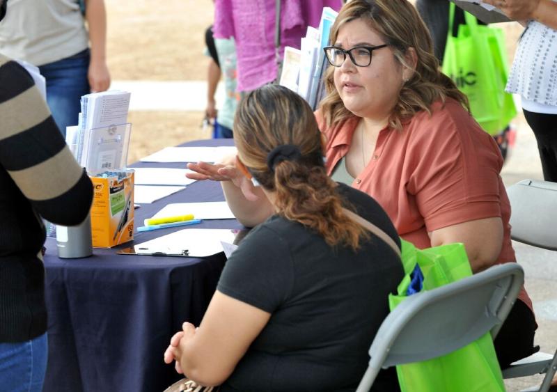 Riverside County Department of Public Social Services employee Ilse Gonzalez works with a family applying for food assistance benefits during a community health fair at Arlanza Elementary School in Riverside, Ca., July 30, 2022. (Contributing Photographer/John Valenzuela)