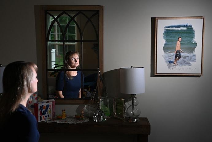 Cheryl Chafos is reflected in a mirror beside a photo of Zach. (Matt McClain/The Washington Post)