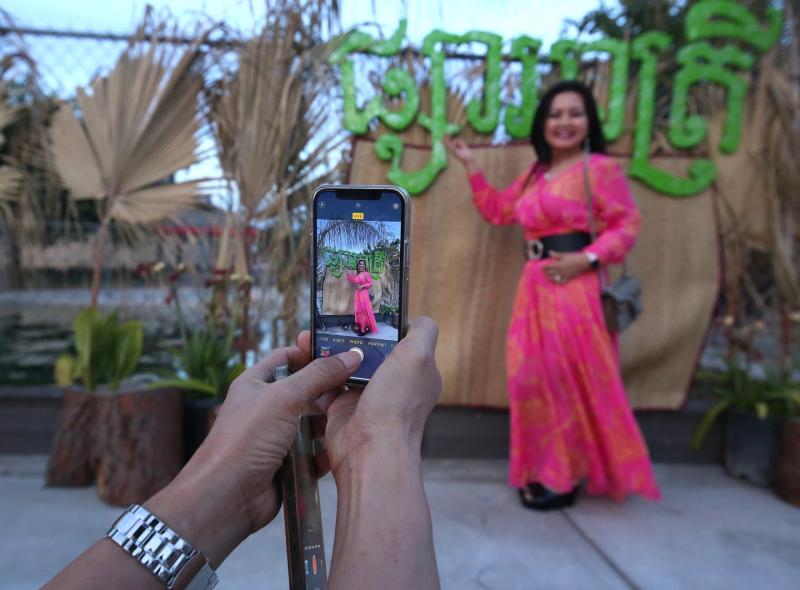 Gary Kazanjian/ Nana Chhum has a friend grab a photo of her at the Cambodian Night Market place shown on Friday, June 3, 2022 in Fresno, Calif.