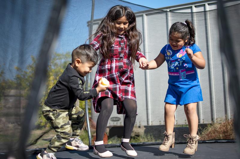 Fernanda Davila, 8, jumps on a trampoline with her siblings, Brandon, 3, and Ariel, 4, outside their Phoenix home on March 8, 2022. MONICA D. SPENCER/THE REPUBLIC
