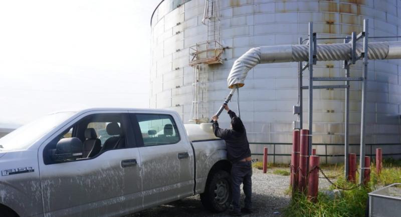 John Kakaruk fills holding tank on a pickup truck for use in Teller's school. The city charges residents 63 cents per gallon for water from the larger hose. (Yereth Rosen)