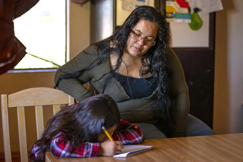 Fernanda Davila, 8, works on homework as her mother, Anarely Jimenez, looks over her progress in their Phoenix home on March 8, 2022. MONICA D. SPENCER/THE REPUBLIC