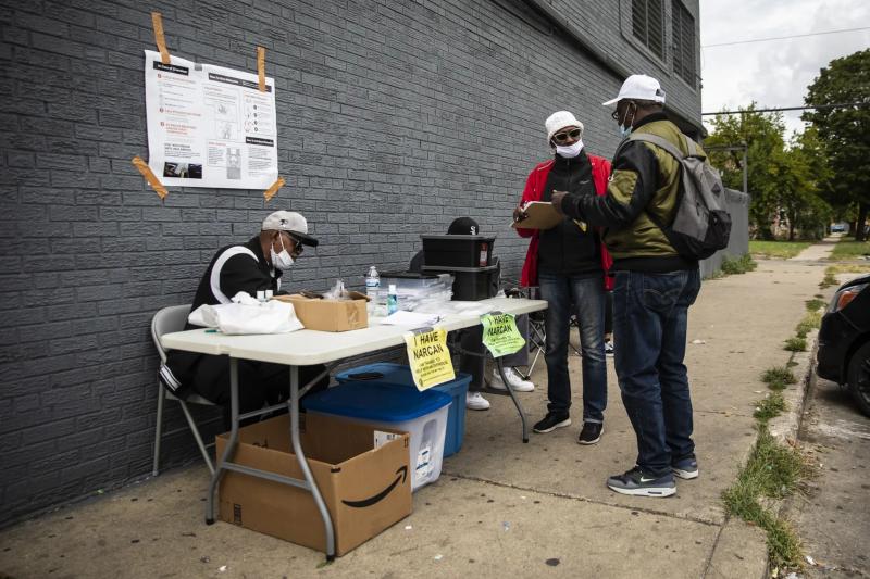 Gail Richardson (center, in red), an outreach worker for the West Side Heroin/Opioid Task Force, provides a man with overdose-reversal drugs including Narcan nasal spray and injectable naloxone along with a syringe. The outreach workers had set up a table near Roosevelt Road and South Albany Avenue on the West Side. Ashlee Rezin / Sun-Times