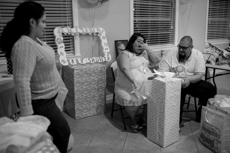 Maria Hernandez opens presents with her partner, Angel Espinoza, as they finish preparations for their baby shower. The couple had been trying to have a child for several years and were excited to celebrate the arrival of their daughter. (Josie Norris)