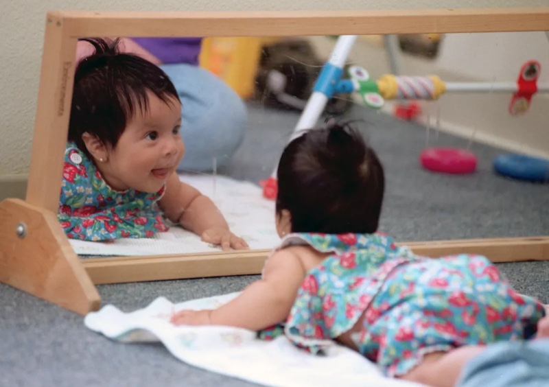 A 4-month-old tries to focus her attention on a mirror in the infant care room at a child care center. Amid an overall shortage of affordable child care, the need for infant care in particular is most acute.(Boris Yaro / The Los Angeles Times)