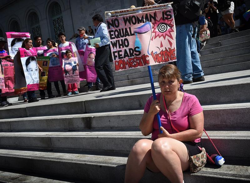 A woman protests against domestic violence as she joins other women's rights advocates in an International Women's Day march in downtown Los Angeles, California on March 8, 2015. AFP PHOTO/ MARK RALSTON (Photo credit should read MARK RALSTON/AFP via Getty Images)